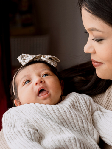 Hispanic mom taking care of her newborn baby of hers while she holds him in the arms of her-latin mother and daughter at home.